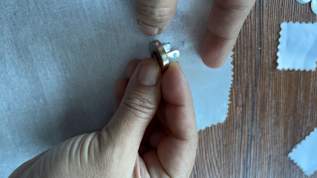 inserting the legs of the magnetic snaps throught the holes